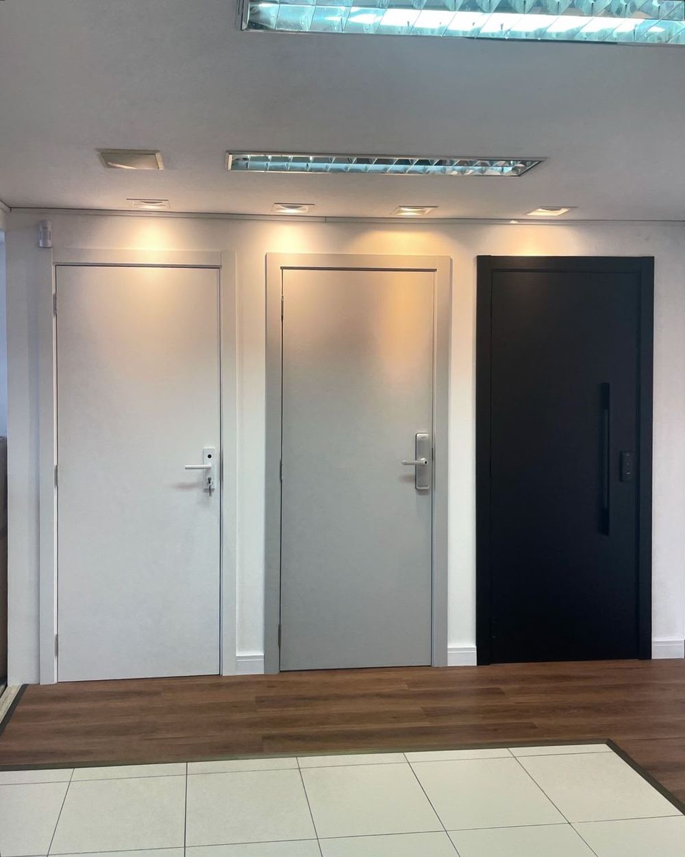 Portas de alto padrão com ferragens pretas em corredor residencial Lumine